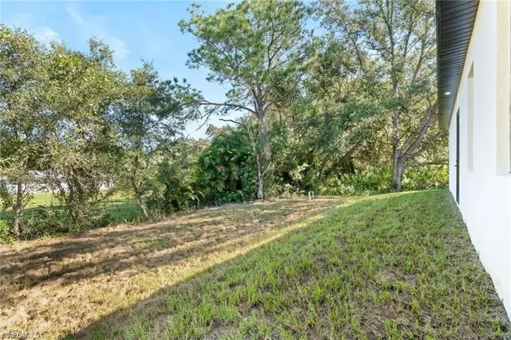 Expansive backyard with a sloped lawn and mature trees