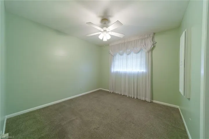 Interior space featuring neutral wall tones, wall-to-wall carpeting, and a multi-blade ceiling fan with integrated lighting