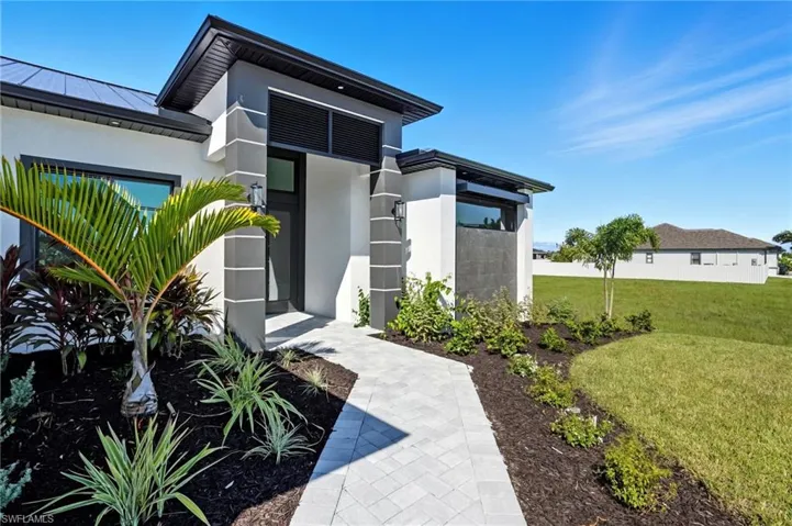 View of exterior entry featuring a yard, a standing seam roof, stucco siding, a metal roof, and solar panels