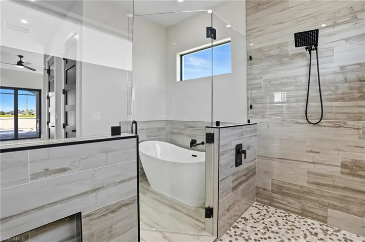Bathroom with a shower stall, a freestanding bath, and tile walls
