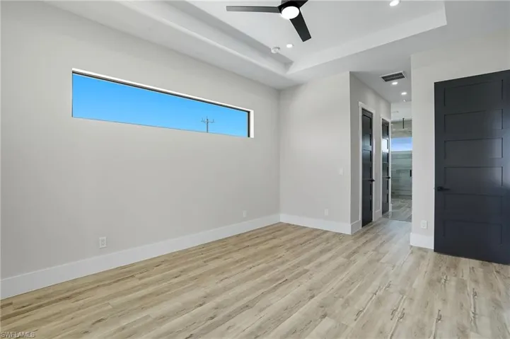 Unfurnished room featuring a tray ceiling, light wood finished floors, ceiling fan, and recessed lighting