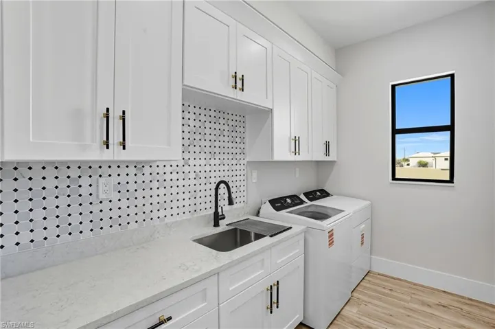 Laundry area featuring light wood-style floors, cabinet space, and washing machine and dryer