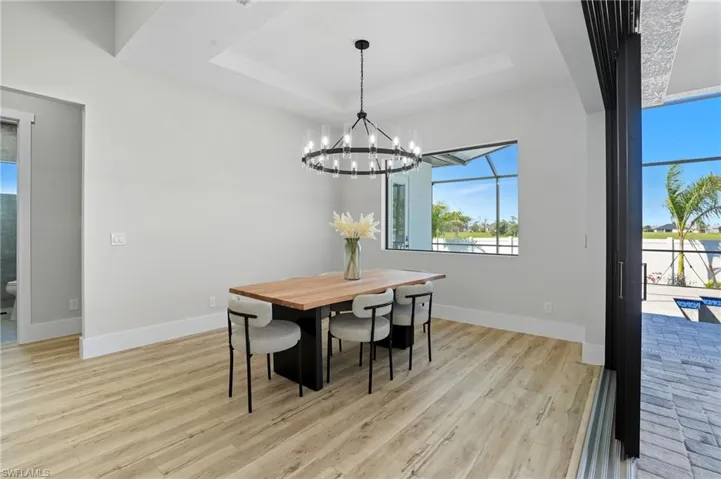 Dining space featuring light wood-style floors, a raised ceiling, and a chandelier