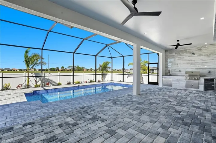 Outdoor pool with glass enclosure, a ceiling fan, area for grilling, a sunroom, and a patio
