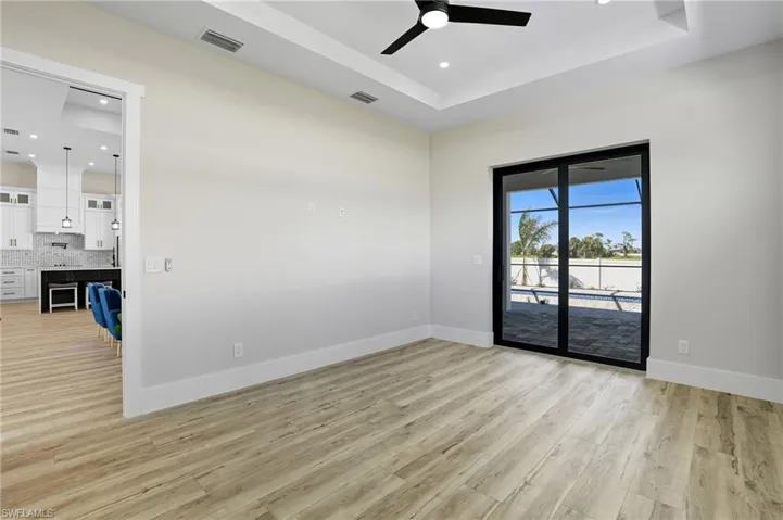 Empty room featuring recessed lighting, light wood-style flooring, a tray ceiling, and a ceiling fan