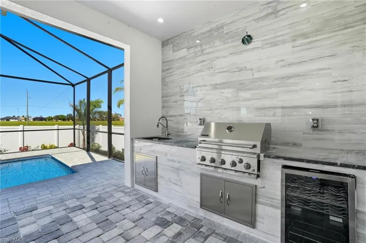 View of patio with a sunroom, beverage cooler, a lanai, and an outdoor kitchen