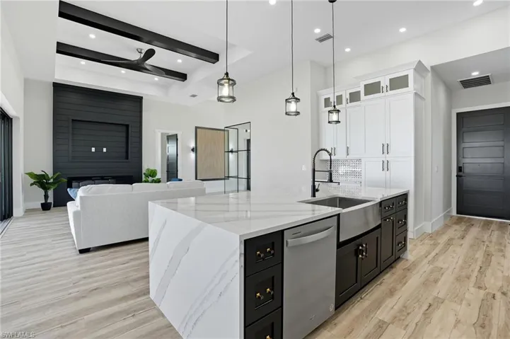 Kitchen featuring dark cabinetry, light stone counters, hanging light fixtures, white cabinetry, and recessed lighting