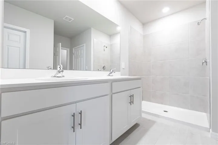 Bathroom featuring tiled shower and vanity