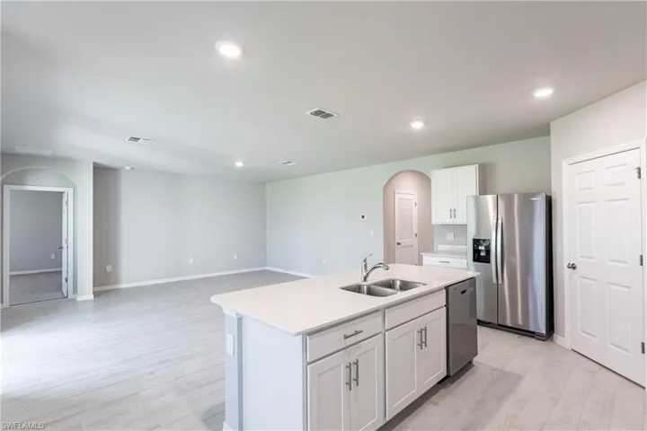 Kitchen featuring a kitchen island with sink, stainless steel appliances, sink, white cabinets, and light hardwood / wood-style floors