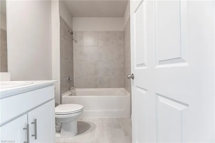 Full bathroom with tiled shower / bath, vanity, and toilet