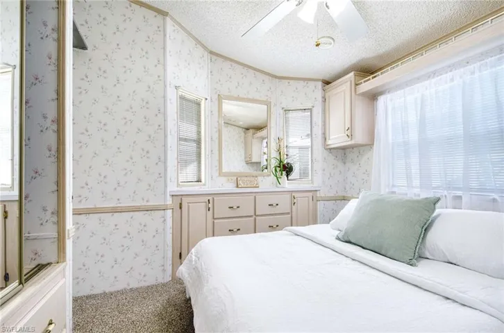 Carpeted bedroom featuring a textured ceiling, ceiling fan, and crown molding
