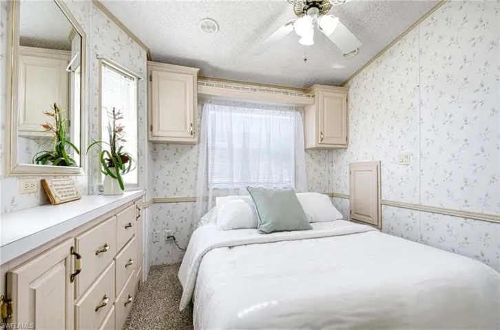 Bedroom featuring ceiling fan, light carpet, and a textured ceiling