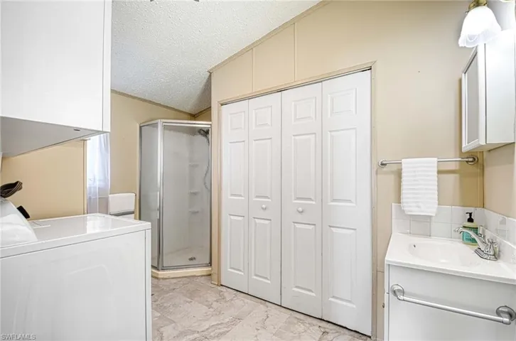 Washroom featuring washer / clothes dryer, sink, and a textured ceiling