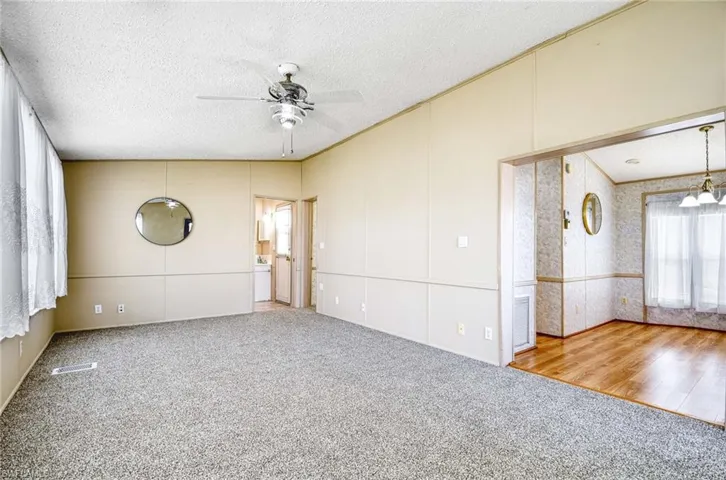 Unfurnished room with carpet flooring, ceiling fan with notable chandelier, and a textured ceiling