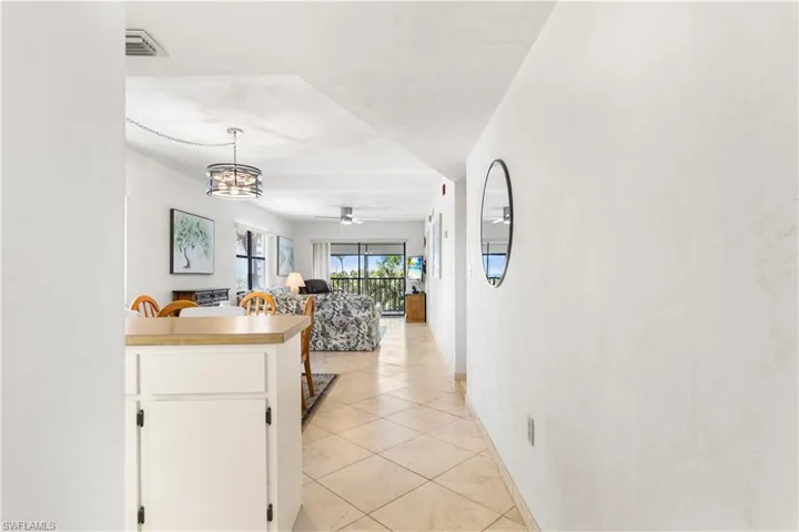Kitchen with decorative light fixtures, white cabinetry, light tile floors, and ceiling fan with notable chandelier