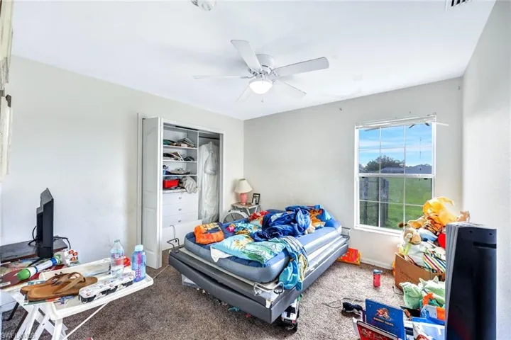Bedroom with ceiling fan, a closet, and carpet flooring