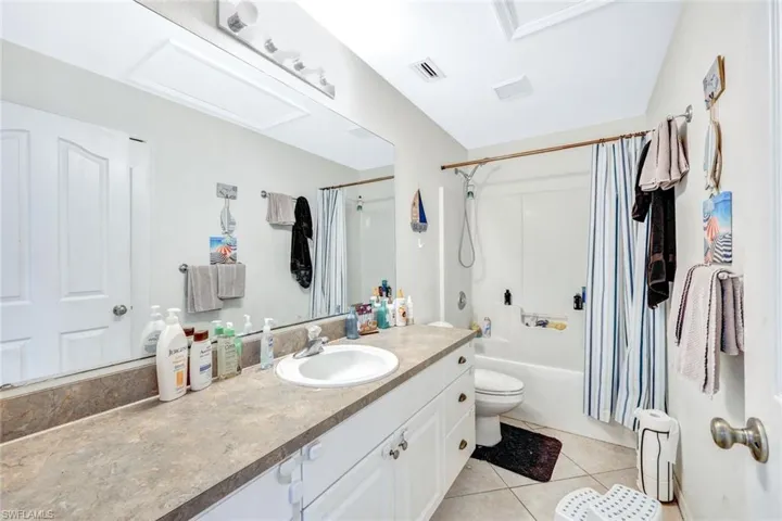 Full bathroom featuring tile flooring, shower / tub combo with curtain, vanity, and toilet