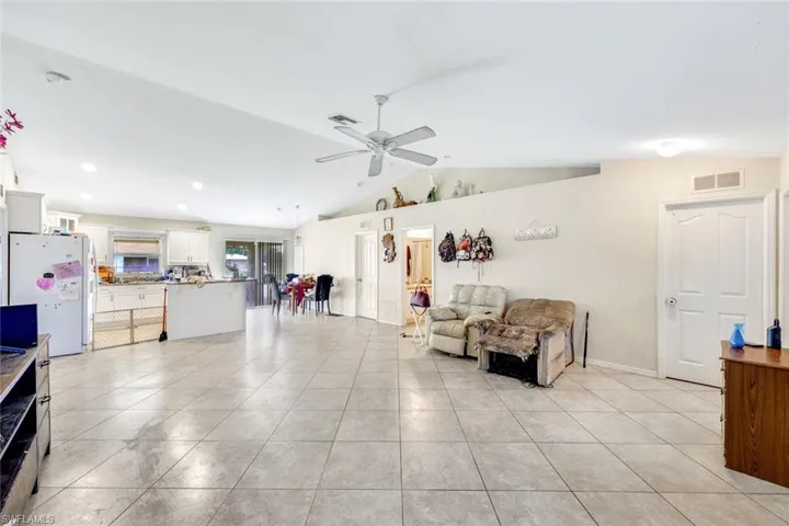 Tiled living room featuring ceiling fan and lofted ceiling
