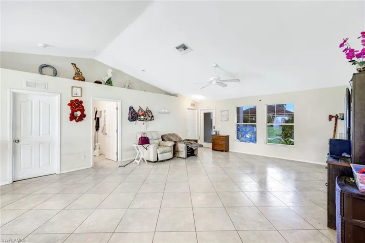 Living room with ceiling fan, lofted ceiling, and light tile floors