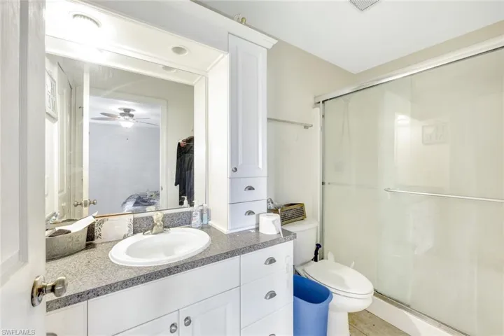 Bathroom featuring walk in shower, vanity, toilet, and ceiling fan