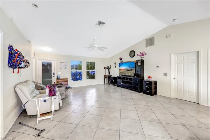 Living room featuring vaulted ceiling, ceiling fan, and light tile floors