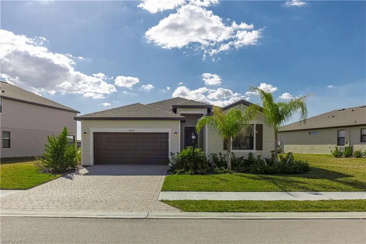 Ranch-style house featuring a front yard, decorative driveway, and an attached garage