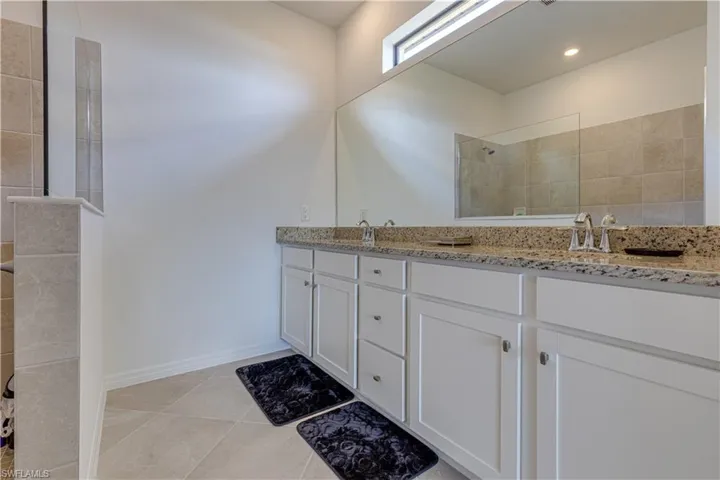 Full bathroom featuring double vanity, a walk in shower, and light tile patterned flooring