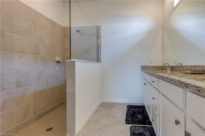 Bathroom with walk in shower, vanity, and light tile patterned floors