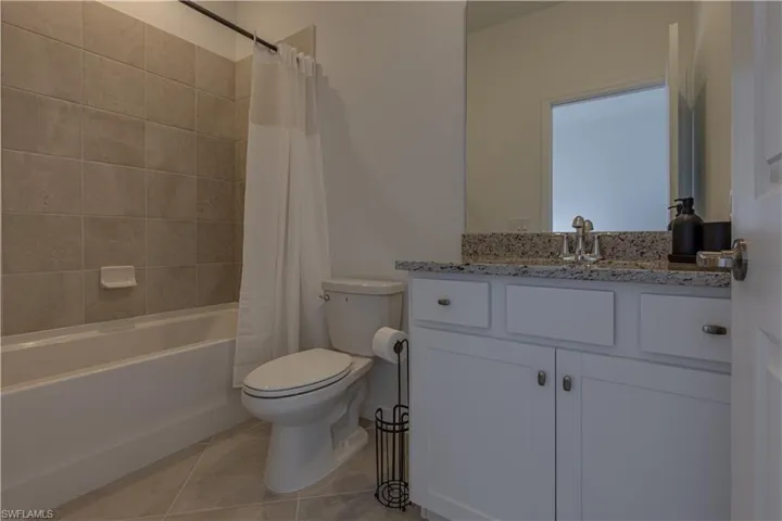 Full bathroom featuring shower / tub combo with curtain, vanity, and light tile patterned floors