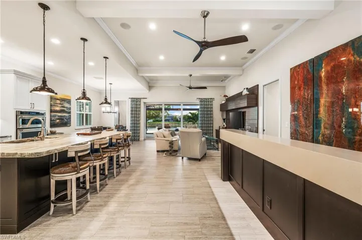 Kitchen featuring decorative light fixtures, white cabinetry, a kitchen bar, crown molding, and stainless steel double oven