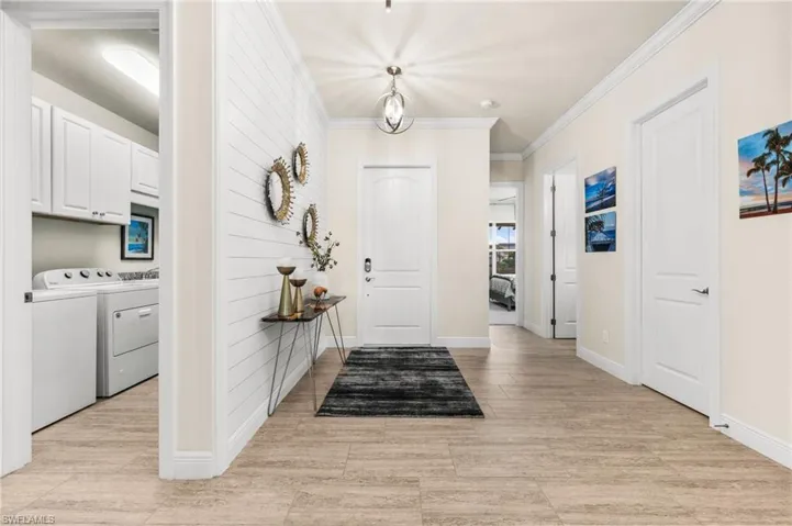 Foyer featuring ornamental molding and separate washer and dryer