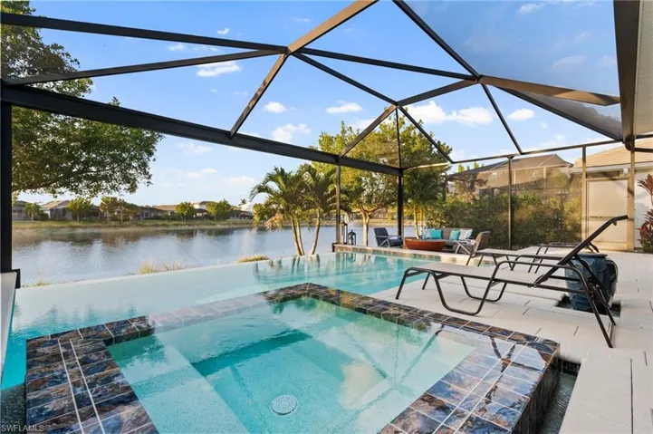 View of pool with a patio, an in ground hot tub, a water view, and glass enclosure