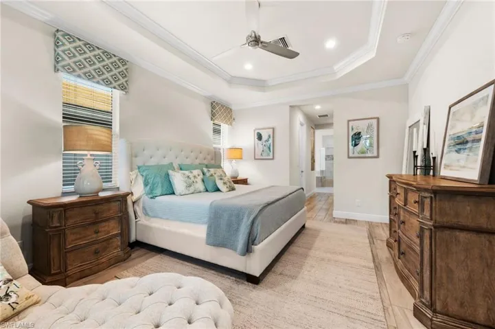 Bedroom featuring ornamental molding, a raised ceiling, ceiling fan, and light wood-type flooring
