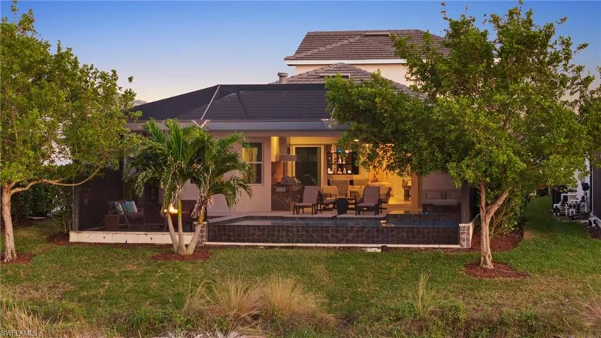 Back house at dusk with a yard and a patio area