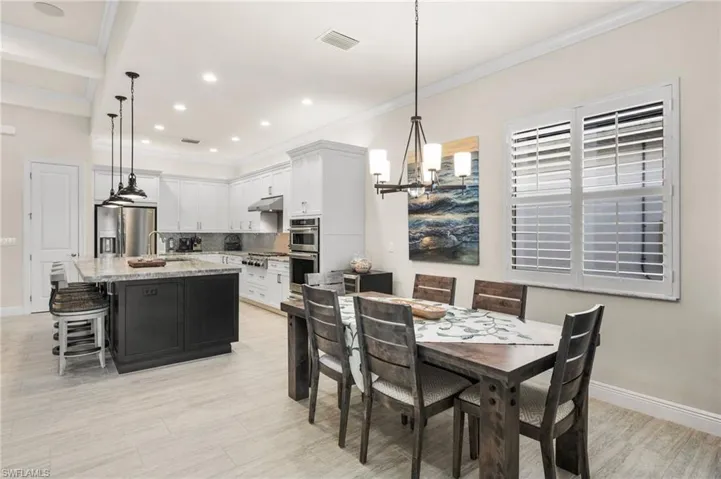Dining area with sink, a notable chandelier, light hardwood / wood-style flooring, and ornamental molding