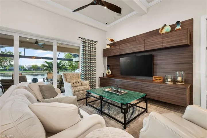 Living room featuring beam ceiling, ornamental molding, light hardwood / wood-style floors, and ceiling fan