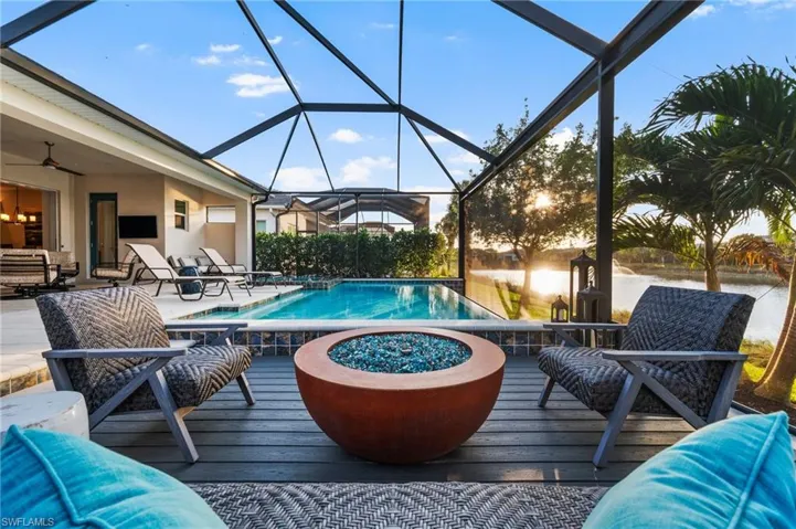 View of pool with a water view, a lanai, an outdoor living space with a fire pit, and ceiling fan