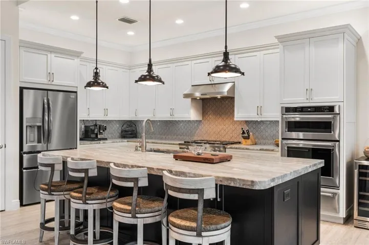 Kitchen with light stone counters, stainless steel appliances, and a center island with sink