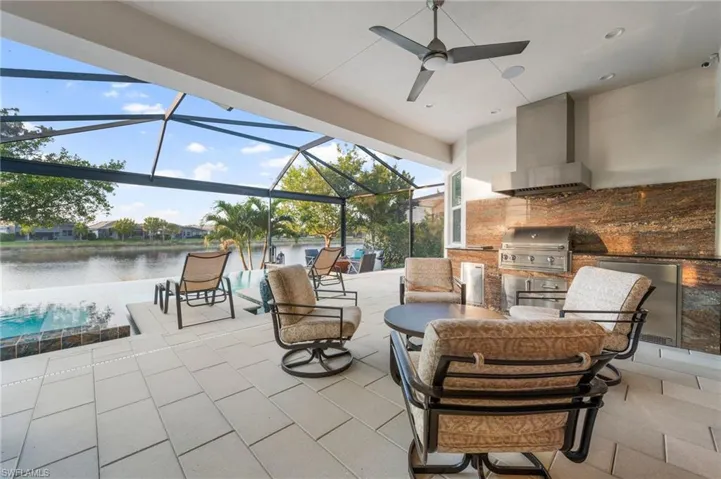 View of patio / terrace with a water view, grilling area, a lanai, and exterior kitchen