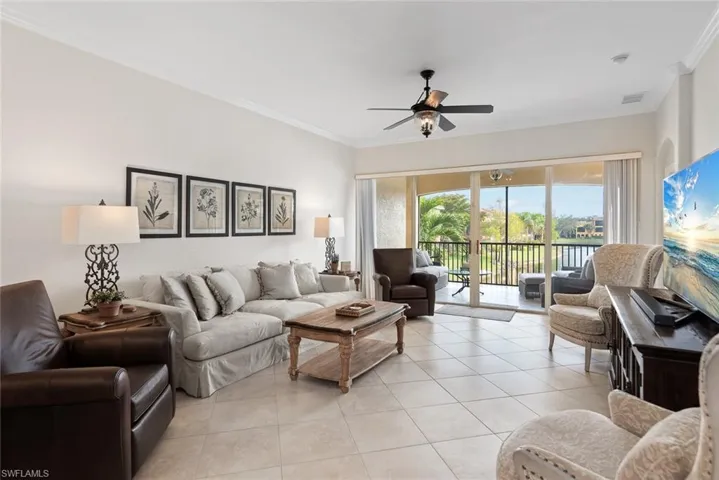 Living room featuring ceiling fan, ornamental molding, and light tile patterned floors