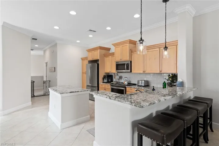 Kitchen with kitchen peninsula, stainless steel appliances, backsplash, and light stone counters