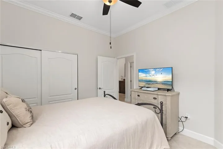 Bedroom with ceiling fan, ornamental molding, and a closet
