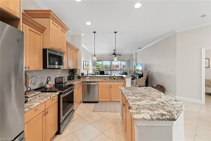 Kitchen with stainless steel appliances, light tile patterned floors, a kitchen island, ceiling fan, and light brown cabinets