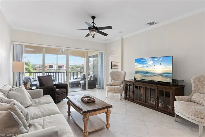Tiled living room with ceiling fan and crown molding