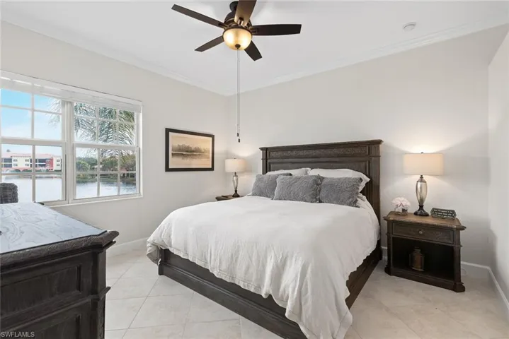 Tiled bedroom with ceiling fan, crown molding, and a water view