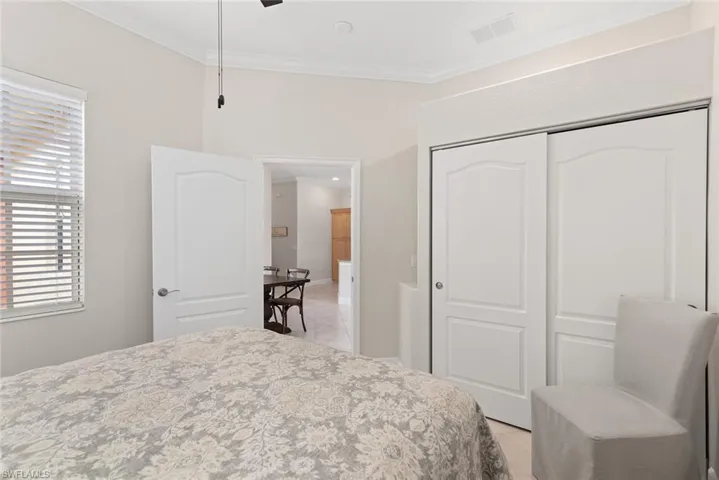 Tiled bedroom with a closet, ceiling fan, and crown molding