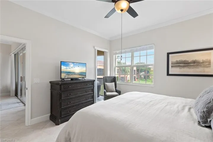Bedroom with ceiling fan, ornamental molding, and light tile patterned floors