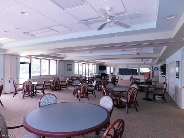Dining space with ceiling fan, a raised ceiling, and carpet floors