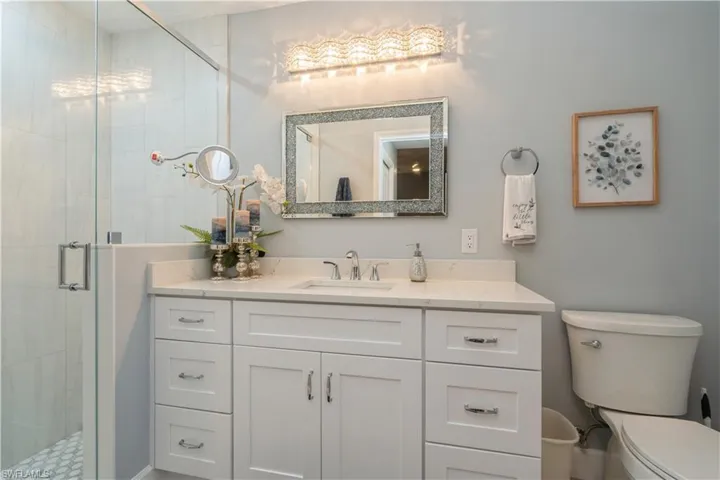 Bathroom with toilet, vanity, and a shower with shower door