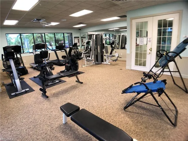 Exercise room with carpet floors, a paneled ceiling, and french doors